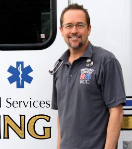 Gary Heigel EMS instructor at RCC posing in front of a training ambulance