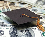 stack of money with a graduation cap on top