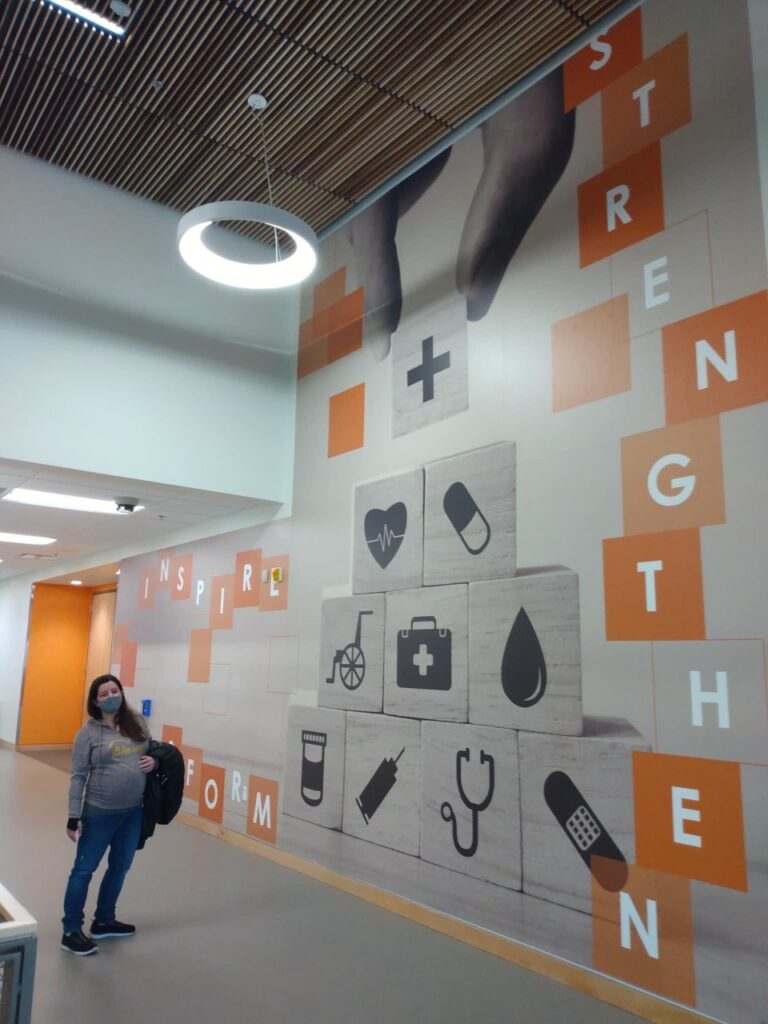 Whitney Barnard is pictured in front of a mural she helped design in the RCC Health Professions Center.