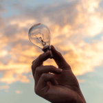 holding a lightbulb to the sky as a visual representation of innovation