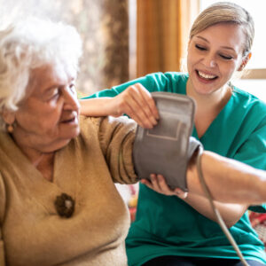 Female caretaker measuring senior woman's blood pressure at home